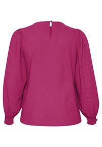 Blouse magenta à manches longues en tissu texturé, avec poignets froncés, manches bouffantes et un petit trou clé dans le dos avec fermeture à bouton.
