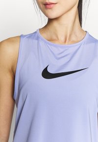 Top sportivo viola senza maniche con logo Nike nero, caratterizzato da un design senza maniche, scollatura rotonda e texture di tessuto liscia.