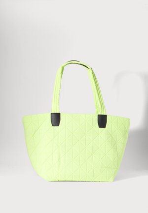 Vatteret neon gul tote-taske med sorte håndtagsaccents, der har en blød stoftekstur og en rummelig, trapezform.