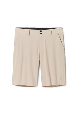 Beige shorts gjorda av lättviktsmaterial; har två framfickor, en svart midja och en logotyp med färgade detaljer på vänster ben.