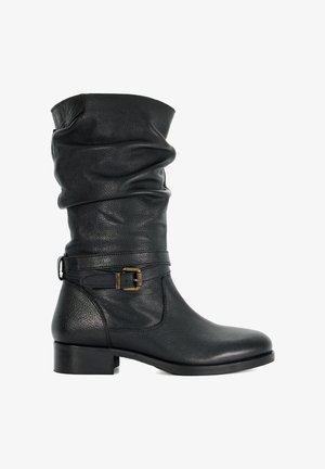 Botte noire en cuir jusqu'au genou avec une tige décontractée, ornée d'une boucle latérale et d'un talon épais. Texture lisse, design minimaliste.