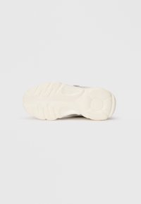 Σόλα αθλητικού παπουτσιού σε ανοιχτό χρώμα με υφή για καλύτερη πρόσφυση και κυκλικό λογότυπο, φωτογραφισμένη πάνω σε λευκό φόντο.