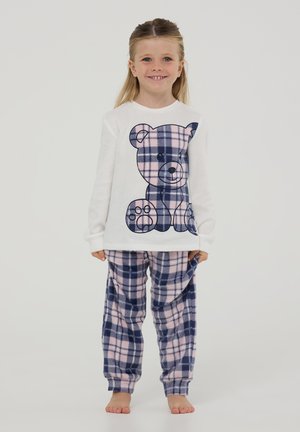 Maglione bianco in pile con una grande grafica di un orsetto di peluche a quadri blu navy e rosa, abbinato a pantaloni a quadri in flanella blu navy e rosa.