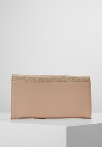 Beige laukku käsivarteen, jonka pinnassa on tekstuuria ja joka on koristeltu kultaisella kimalteella ylhäällä. Laukku on suorakaiteen muotoinen ja sen linjat ovat siistit.