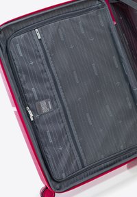 Maleta rígida con un exterior de color rosa brillante. El interior cuenta con un bolsillo de malla gris con cremallera y un forro de tela con estampados temáticos de viajes.