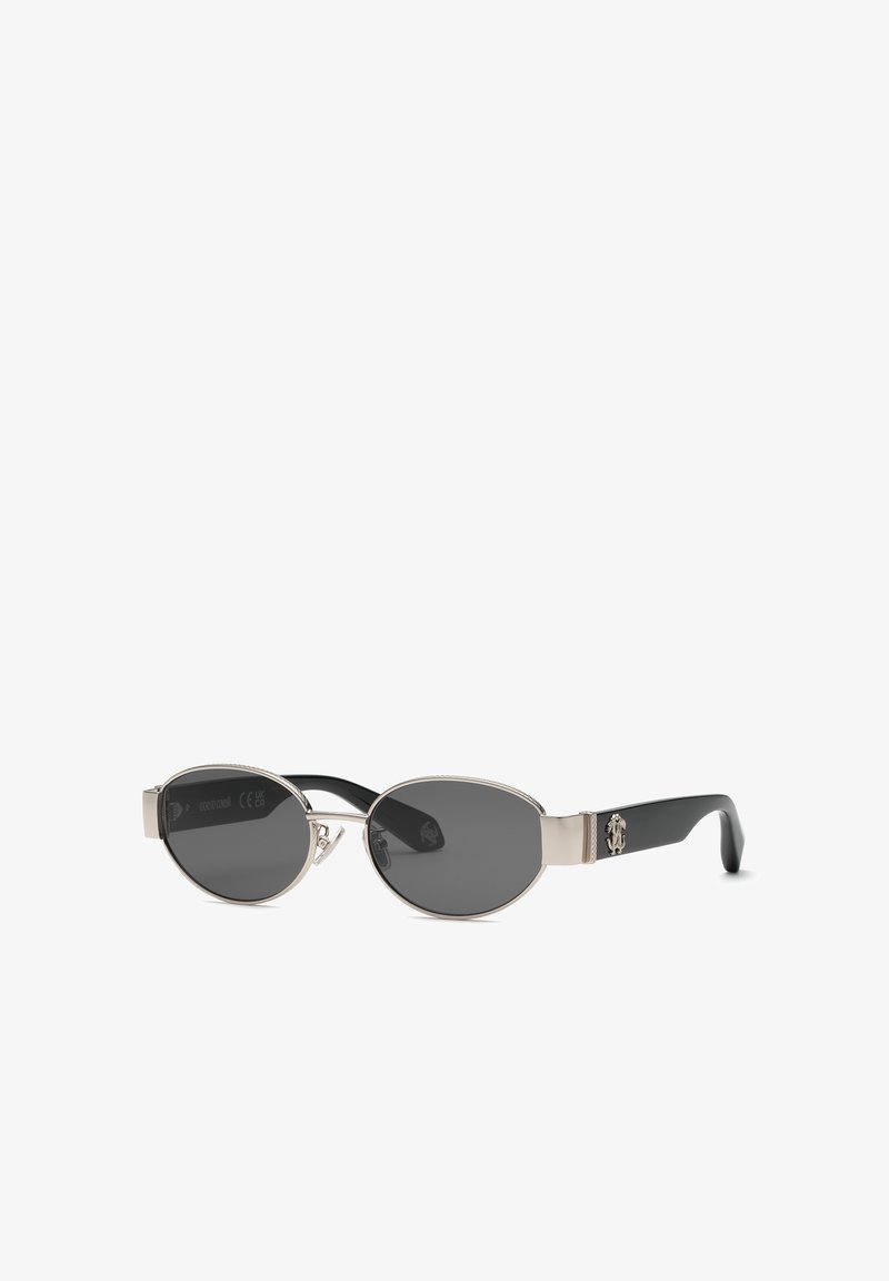 Lunettes de soleil ovales avec verres teintés noirs, monture métallique argentée et branches noires avec un petit emblème argenté de chaque côté.