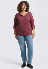 Rød ternet skjorte med V-hals, treskårede ærmer og op rullede manchetter, kombineret med lyseblå straight-leg jeans og sorte støvler.