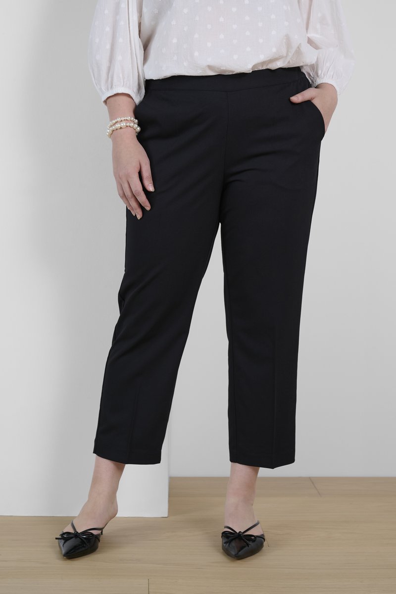Schwarze, kurze Hose mit glatter Oberfläche und seitlichen Taschen. Kombiniert mit schwarzen Ballettschuhen mit Schleifenakzenten.