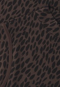 Tissu marron avec un motif léopard noir irrégulier et des lignes de couture visibles le long des coutures.