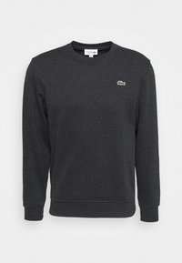 Mörkgrå sweatshirt i mjukt material, med rundad halsringning, långa ärmar och en liten grön Lacoste-logotyp på bröstet.