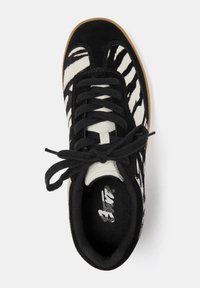 Sneaker a strisce zebra in bianco e nero con tomaia in suede, lacci neri e suola in gomma naturale. Presenta un collare imbottito per il comfort.