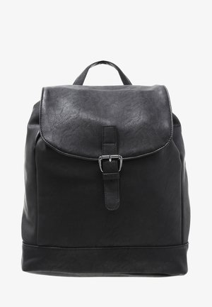 Czarny plecak ze sztucznej skóry z klapą zabezpieczoną srebrną klamrą i górnym uchwytem, przedstawiony na białym tle.