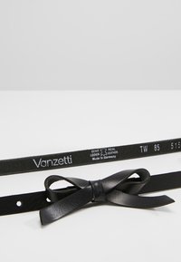 Cinturón de cuero negro con acento de lazo; marcado con "Vanzetti" y detalles de tamaño; textura suave, orificios ajustables para el cierre.