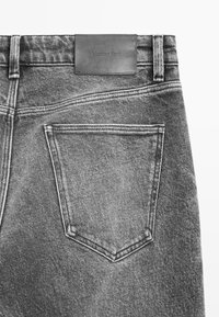 Szare dżinsy z denimu z skórzaną metką Massimo Dutti, widoczne szwy oraz jedna tylna kieszeń o klasycznym kształcie i fakturze.