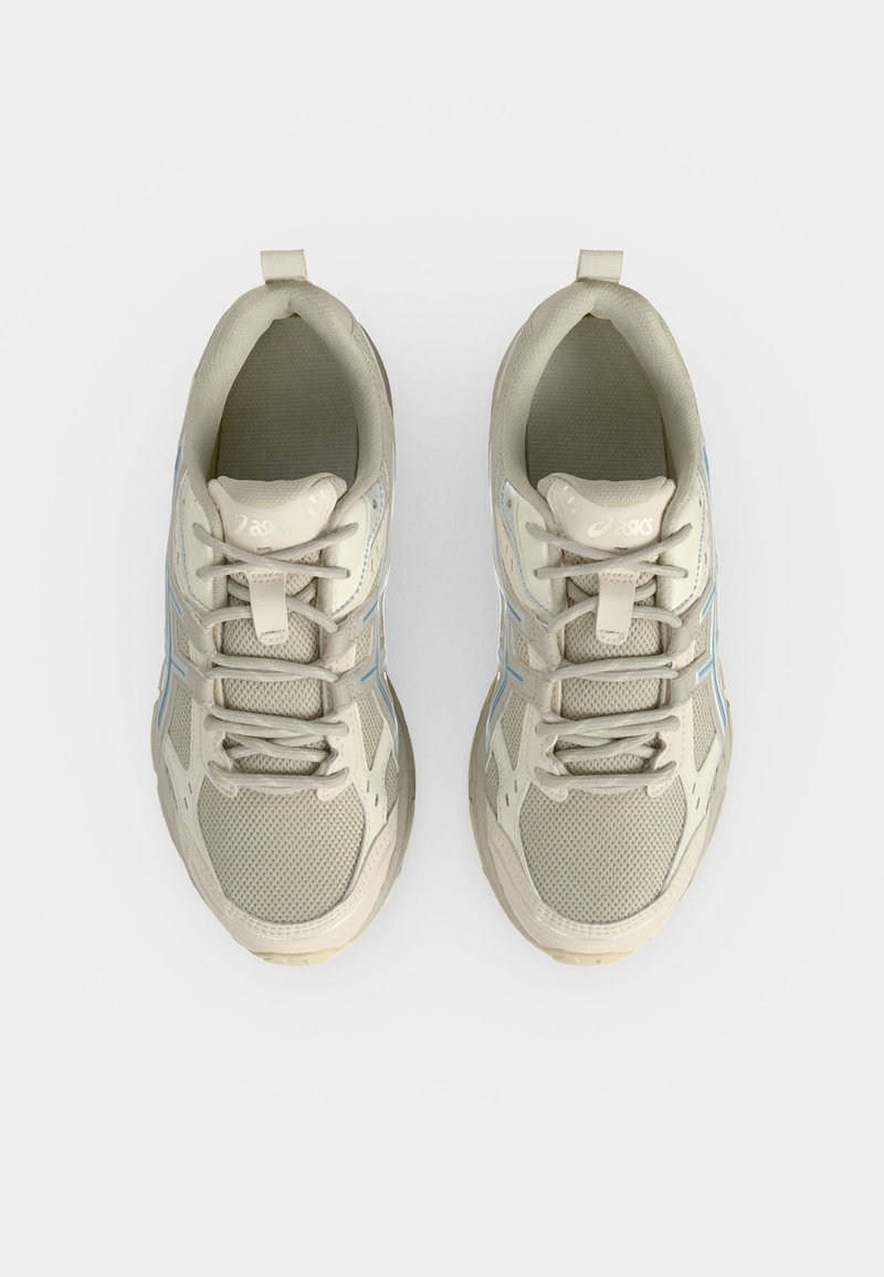 Par de zapatillas de running beige con superiores de malla y sintético, atadas, vista desde arriba sobre fondo blanco.