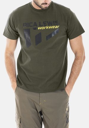 T-shirt en coton vert à col rond, avec un texte noir et jaune et un design graphique à motifs sur le devant.