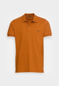 Koszulka polo z krótkim rękawem w pomarańczowym kolorze z bawełny, z kołnierzykiem, zapięciem na dwa guziki i małą naszywką z logo na klatce piersiowej.