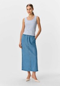 Gestreifter ärmelloser Top in Weiß und Blau, kombiniert mit einem langen Jeansrock. Der Rock hat einen elastischen Taillenbund und seitliche Taschen. Beigefarbene Blockabsatz-Mules.