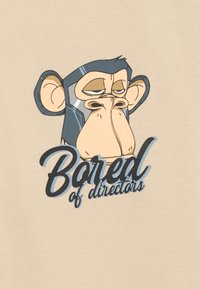 Camiseta color beige con un mono de dibujo animado que tiene una expresión de aburrimiento. El texto en la parte inferior dice "Aburrido de directores" en una fuente estilizada azul.