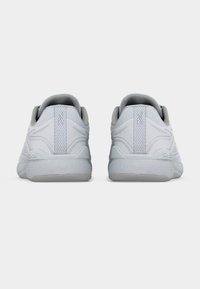 Ζευγάρι λευκών αθλητικών παπουτσιών εμφανίζεται από πίσω με υφασμένους πάτους και διακριτικές λεπτομέρειες λογοτύπου στη φτέρνα και στην ταμπέλα της φτέρνας.