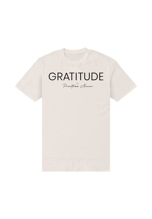 Camiseta beige de manga corta con "GRATITUDE by Prentiss Nixon" impreso en negro en el centro delantero.