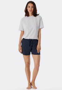 Lys grå bomull T-skjorte kombinert med marineblå shorts med hvite vertikale striper. Shortsen har en avslappet passform og sydd midjebånd.
