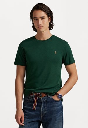 Mørkegrønn bomull T-skjorte med rund hals og korte ermer. Har en liten brodert logo på brystet. Brukt med jeans og et flerfarget belte.