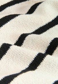 Off-white gebreide stof met opvallende zwarte strepen, met een textuur oppervlak waar de steken zichtbaar zijn en een zachte, flexibele structuur.