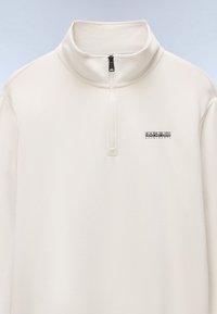 Weißer Pullover mit Viertel-Reißverschluss aus weichem Stoff, ausgestattet mit einem hohen Kragen, Reißverschluss und kleinem schwarzem Logo auf der Brust.