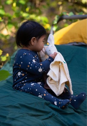 Marineblaue Schlafanzug-Set mit weißen Mond- und Sternmustern, mit einem Kind, das eine weiche, weiße Hasenpuppe mit einer cremefarbenen Decke hält.