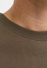 Donkergroene katoenen t-shirt met een ribbelkraag en een soepele textuur, voorzien van stikseldetails bij de halslijn.