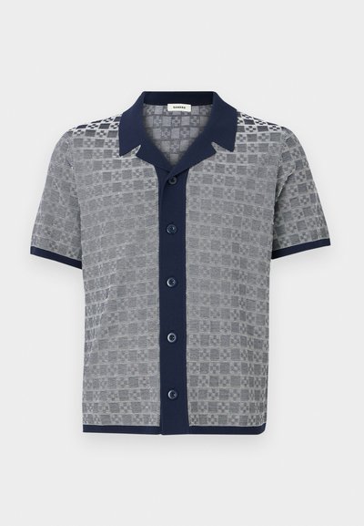Chemise à manches courtes avec col et patte de boutonnage bleu marine, présentant un motif texturé gris et blanc et une bordure bleu marine aux manches et à l'ourlet.