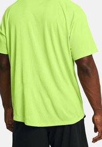 Kortärmad, figursydd träningsshirt i ljus limegrön färg, tillverkad av texturerat tyg. Sömlös design med rundad nederkant.