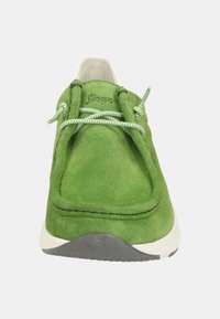 Sneaker verde in suede con sistema di lacci elastici, suola in gomma bianca e dettagli cuciti. Il design è minimalista e si infila facilmente.