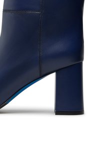 Stivale ankle blu navy con finitura in pelle liscia, tacco quadrato e suola blu a contrasto. Presenta cuciture pulite lungo i lati.