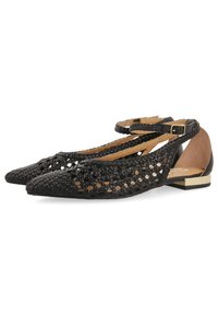 Ballet flats tressées noires avec un bout pointu, un design découpé, une lanière à la cheville et un accent doré sur le talon. Matériau en cuir avec une finition texturée.