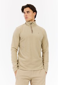 Beige fleece sweatshirt med halvlukket krave, med en tekstureret overflade og diskret logo detalje. Lange ærmer og normal pasform.