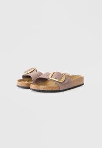 Bruna slidesandaler med två breda remmar, guldspännen, korkfotsäng och en texturerad svart gummisula. En enkel och funktionell design.