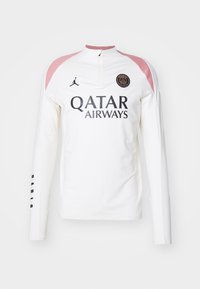 Valkoinen pitkähihainen paita, jossa on vaaleanpunaiset olkapääkorostukset, urheilulogo rinnassa ja musta teksti "Qatar Airways". Vetoketjukaulus ja hihansuut.