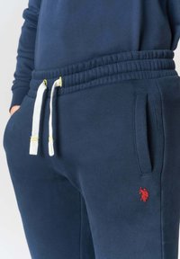 Pantaloni della tuta blu navy con vita elasticizzata, coulisse bianche e logo rosso. Dotati di tasche laterali e tessuto morbido e strutturato.