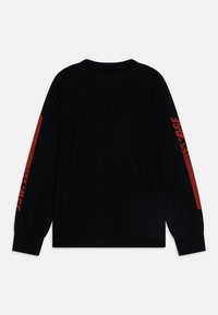 Cămașă neagră cu mâneci lungi, cu accente roșii pe mâneci, având un design grafic și un guler rotund. Fabricată din material de bumbac moale.
