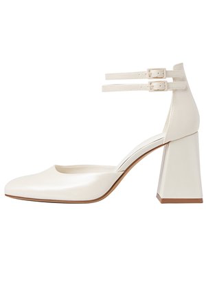 Chaussure à talon haut en cuir blanc avec bout arrondi, brides à la cheville et talon bloc. Texture lisse avec un design minimaliste et une couleur neutre.