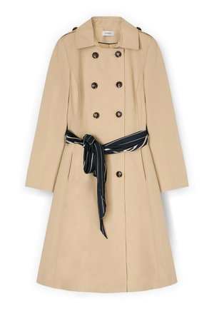 Beżowy prochowiec dwurzędowy z dużym kołnierzem, ciemnymi okrągłymi guzikami, długimi rękawami, bocznymi kieszeniami oraz czarnym paskiem w paski związanym w talii.