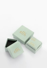 Trois boîtes à bijoux vert clair avec des logos dorés "elli premium", une fermée, une ouverte montrant l'intérieur noir, et une empilée avec une étiquette sur le dessus.