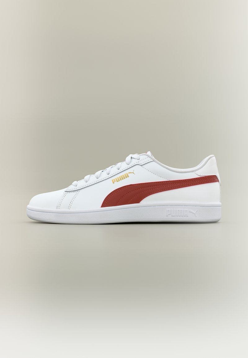 Witte lage Puma sneaker met bordeauxrode streep, gouden Puma-logo, veterluiting en vlakke witte zool op een neutrale achtergrond.