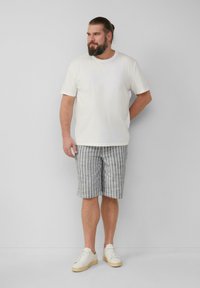 T-shirt blanche à manches courtes, short rayé gris et baskets blanches. Look décontracté avec un design relax et des rayures horizontales.