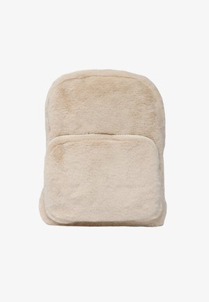 Zaino in finto pelliccia beige con una texture morbida, parte superiore arrotondata, tasca anteriore con zip e design minimalista. Accenti color crema sulle cerniere.