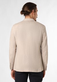 Lichtbeige linnen blazer met een gestructureerd ontwerp, enkele split aan de achterkant en subtiele textuur. Twee knopen bij de mouw en een eenvoudige afwerking.