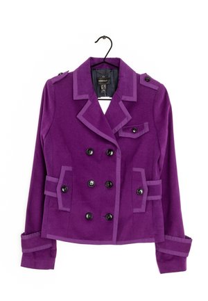 Blazer morado de mujer de doble botonadura con botones negros, cuello con muesca, bolsillos con solapa abotonados y hombreras decorativas en una percha.