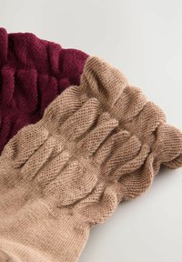 Due paia di guanti senza dita lavorati a maglia: uno in un profondo bordeaux e l'altro in un beige chiaro. Entrambi presentano un design a costine e una texture lavorata.